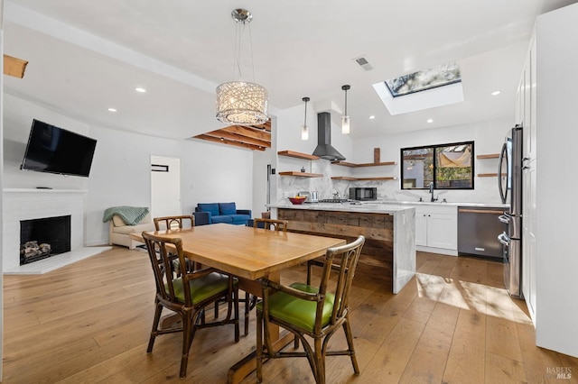 dining space with sink, light hardwood / wood-style floors, and a skylight