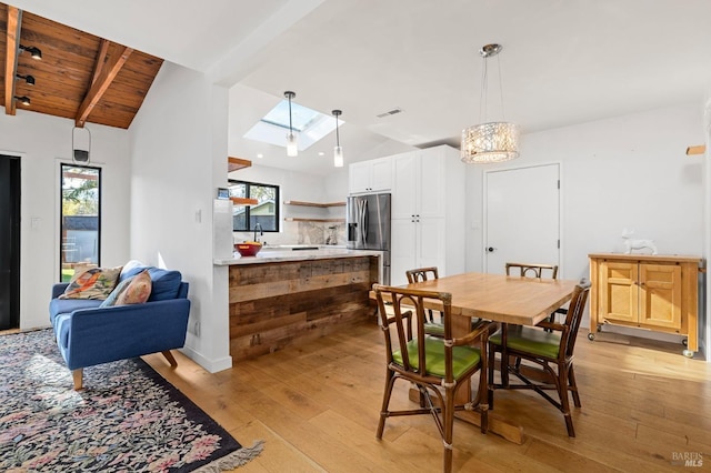 dining space with wood ceiling, vaulted ceiling with skylight, and light hardwood / wood-style flooring