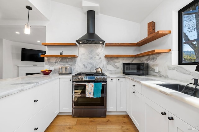 kitchen featuring pendant lighting, white cabinetry, light stone countertops, island exhaust hood, and range with two ovens