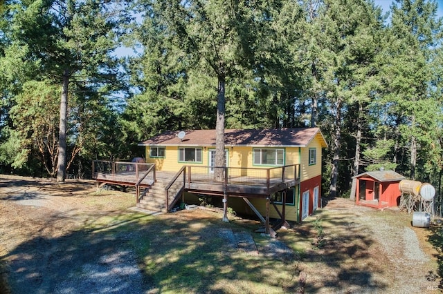 rear view of house featuring a storage unit and a deck