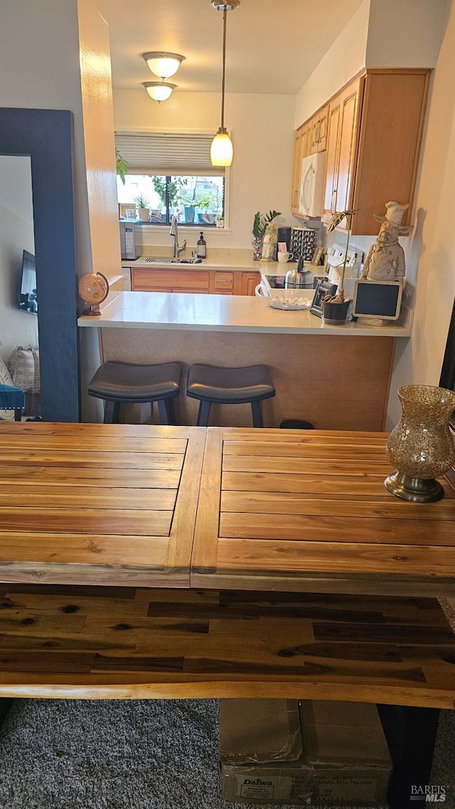 kitchen featuring decorative light fixtures, sink, a breakfast bar area, stove, and kitchen peninsula