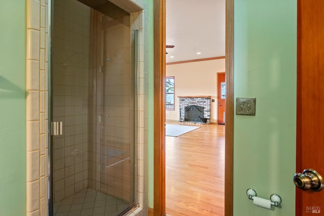 bathroom with a fireplace, an enclosed shower, crown molding, and hardwood / wood-style floors