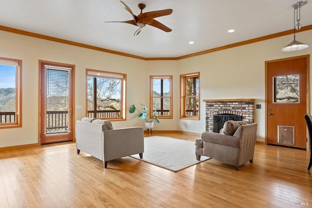 living room featuring light wood-type flooring, ornamental molding, a brick fireplace, and ceiling fan