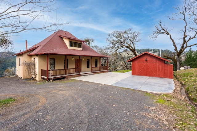 view of front facade with a porch, a garage, and an outbuilding