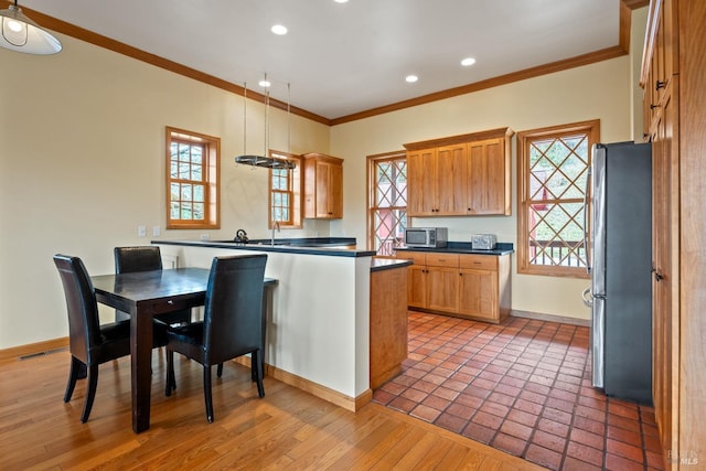 kitchen featuring crown molding, plenty of natural light, stainless steel appliances, and decorative light fixtures