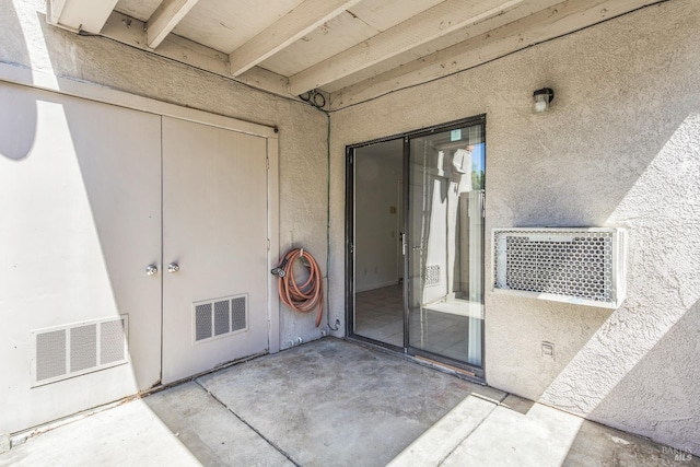 property entrance with a patio, visible vents, and stucco siding