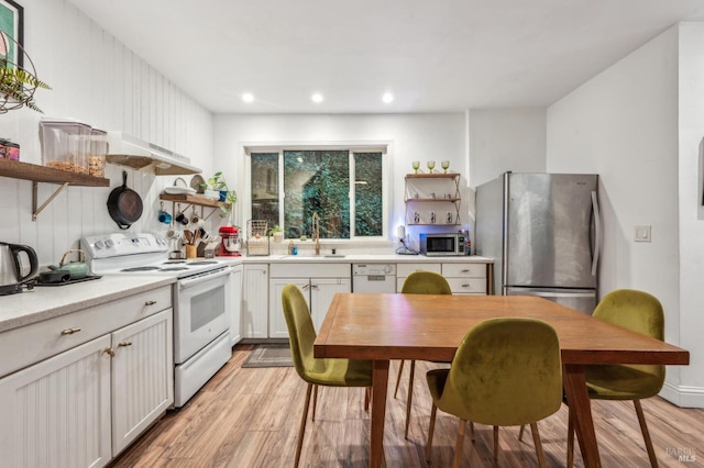 kitchen with stainless steel appliances, sink, white cabinets, and light wood-type flooring