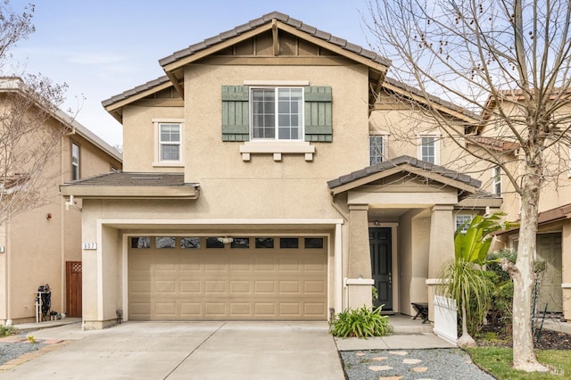 view of front of property with a garage, driveway, a tiled roof, and stucco siding