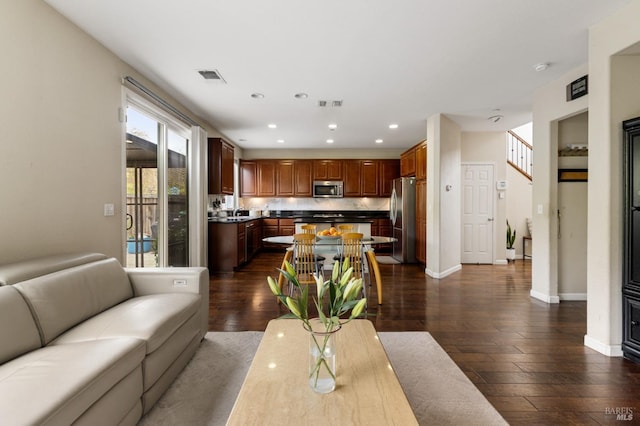 living area featuring baseboards, dark wood-type flooring, visible vents, and recessed lighting