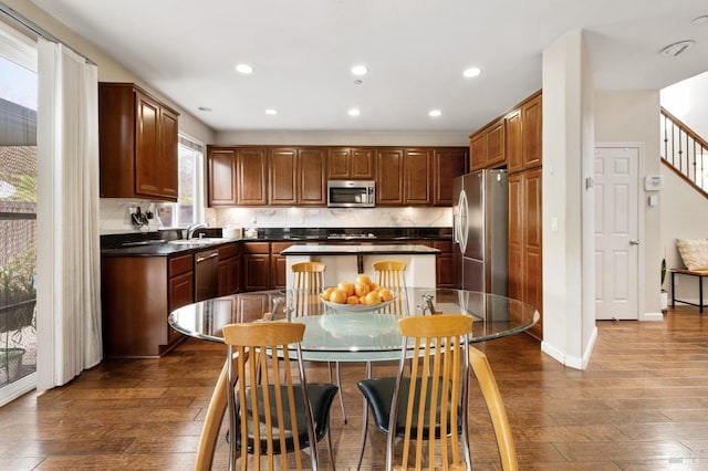 kitchen featuring dark wood-style floors, stainless steel appliances, dark countertops, recessed lighting, and a sink