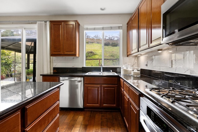 kitchen with appliances with stainless steel finishes, plenty of natural light, a sink, and dark wood-style floors