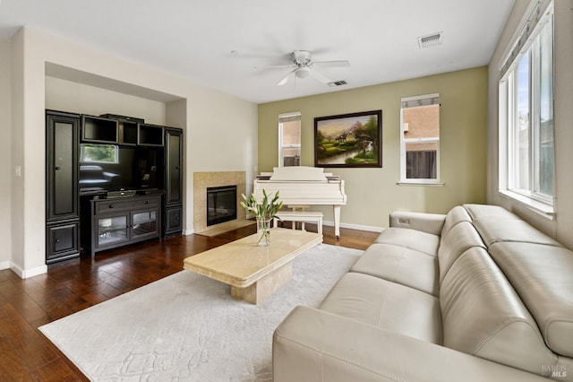 living room featuring a healthy amount of sunlight, a fireplace with flush hearth, visible vents, and dark wood-type flooring