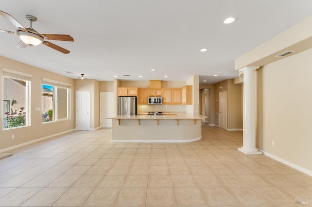 kitchen featuring a peninsula, light brown cabinetry, light countertops, a ceiling fan, and stainless steel appliances