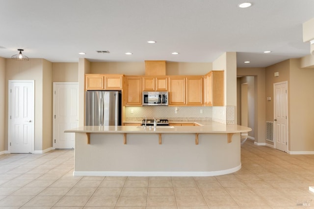 kitchen featuring backsplash, visible vents, appliances with stainless steel finishes, light countertops, and a peninsula