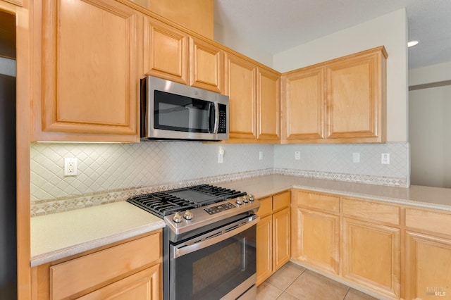kitchen with light countertops, appliances with stainless steel finishes, light brown cabinets, and light tile patterned floors