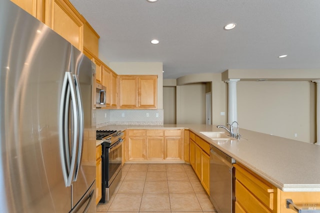 kitchen with light countertops, stainless steel appliances, a sink, and a peninsula