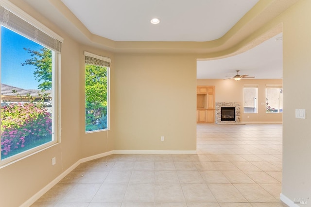 spare room featuring light tile patterned flooring, a healthy amount of sunlight, and a fireplace