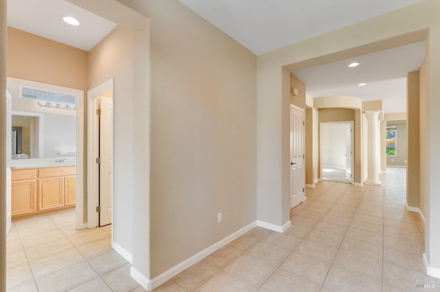 hall featuring ornate columns, recessed lighting, baseboards, and light tile patterned flooring