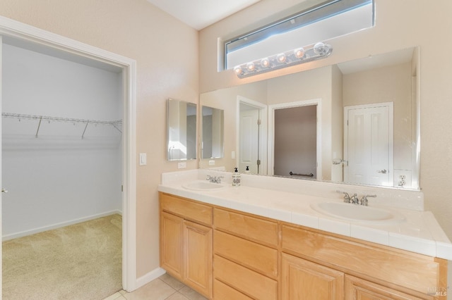 bathroom with double vanity, a sink, tile patterned flooring, and a spacious closet