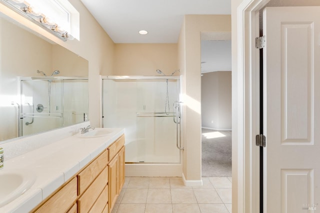 full bath with double vanity, a sink, tile patterned floors, and a shower stall