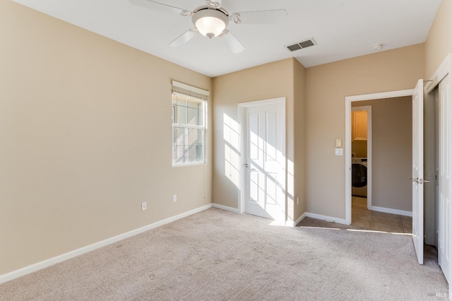 unfurnished bedroom with a ceiling fan, washer / clothes dryer, visible vents, baseboards, and carpet flooring