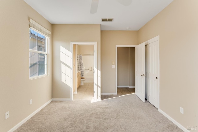 unfurnished bedroom featuring visible vents, carpet flooring, baseboards, and ensuite bath