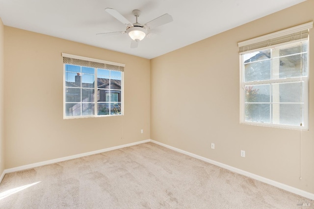 carpeted empty room featuring baseboards, plenty of natural light, and ceiling fan