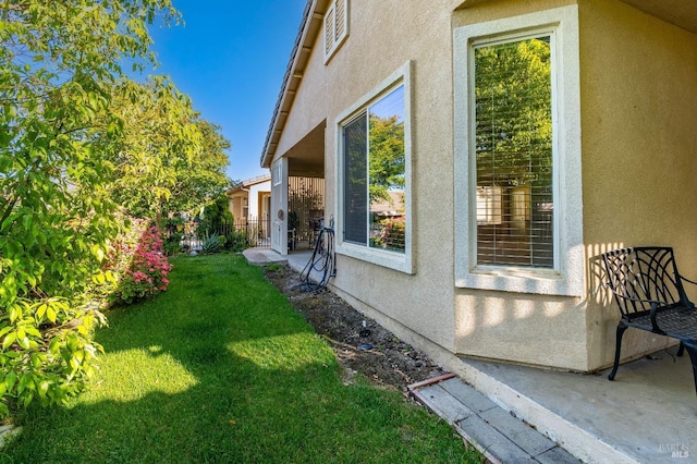 view of side of home with stucco siding and a yard