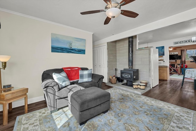 living room featuring ceiling fan, a wood stove, crown molding, and dark hardwood / wood-style flooring