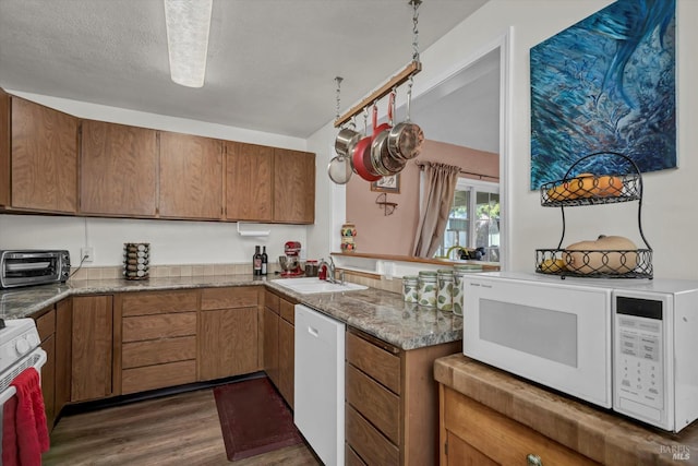 kitchen featuring sink, white appliances, a textured ceiling, and dark hardwood / wood-style floors