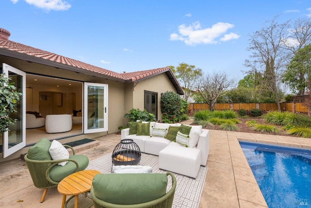 view of patio with a fenced in pool and an outdoor living space with a fire pit