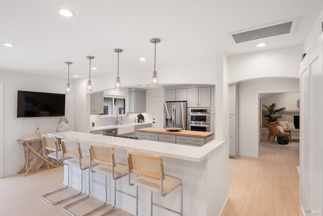 kitchen with stainless steel appliances, decorative light fixtures, a center island, and gray cabinetry