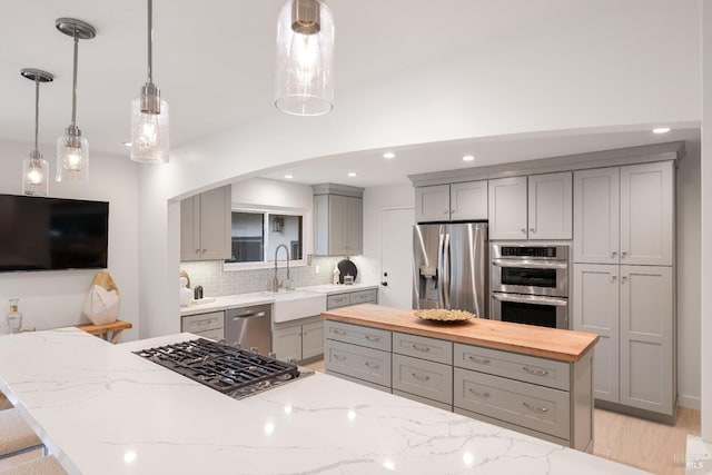 kitchen featuring wood counters, appliances with stainless steel finishes, sink, and gray cabinetry