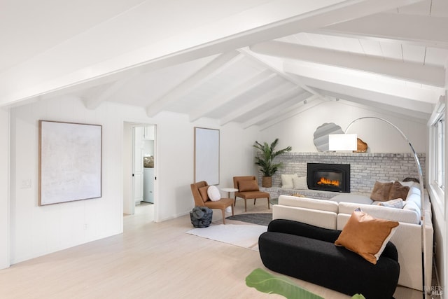 living room with vaulted ceiling with beams, light hardwood / wood-style flooring, and a brick fireplace