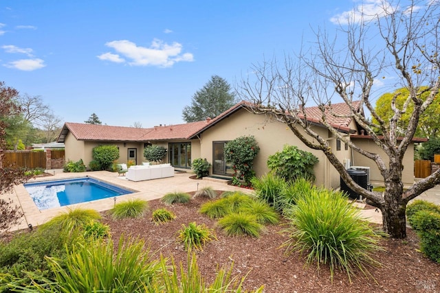 rear view of property with cooling unit, a fenced in pool, and a patio