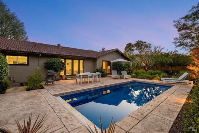 pool at dusk featuring a patio area