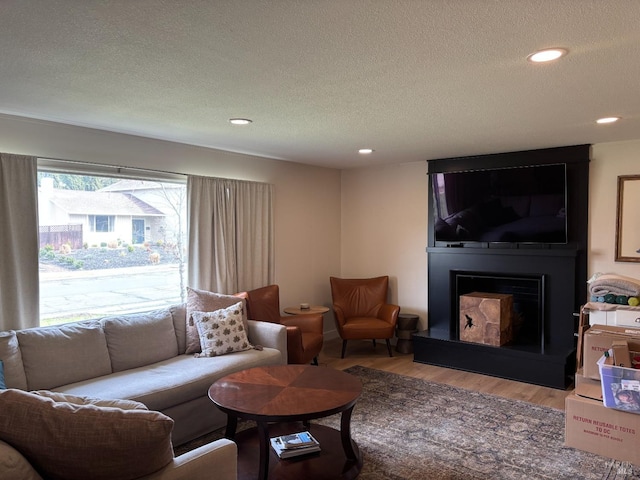 living room with a fireplace, a textured ceiling, and light hardwood / wood-style flooring