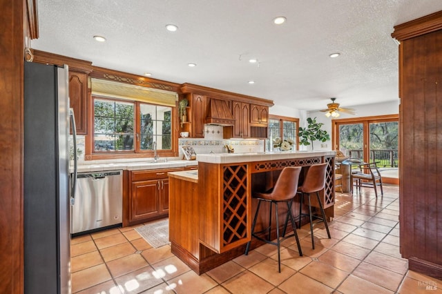 kitchen with appliances with stainless steel finishes, a kitchen island, custom range hood, a kitchen bar, and decorative backsplash