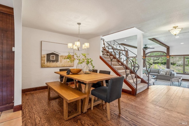 dining space featuring ceiling fan with notable chandelier, wood-type flooring, and a textured ceiling