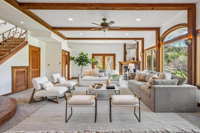 living room featuring ceiling fan, a textured ceiling, light colored carpet, and beamed ceiling