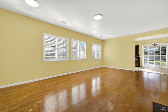 unfurnished room featuring an inviting chandelier and hardwood / wood-style floors