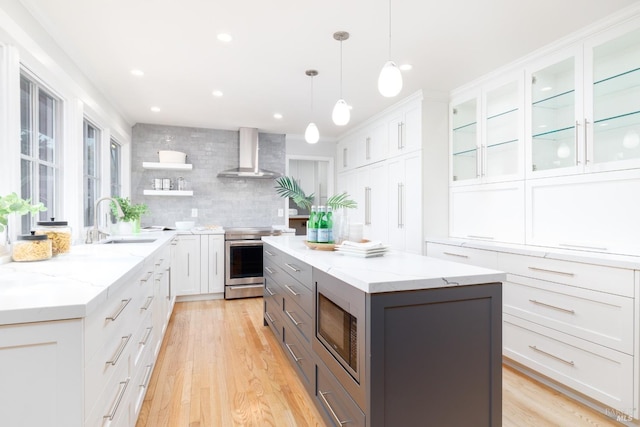 kitchen with electric stove, sink, white cabinetry, and wall chimney exhaust hood