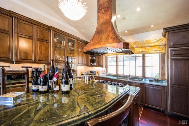 kitchen with sink, premium range hood, dark stone countertops, backsplash, and dark hardwood / wood-style flooring