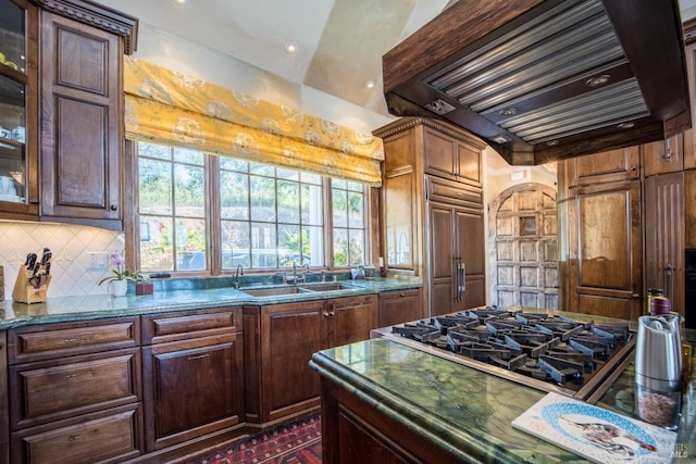 kitchen featuring sink, paneled refrigerator, decorative backsplash, custom exhaust hood, and cooktop