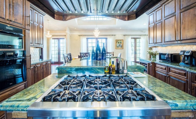 kitchen featuring french doors, a center island, light stone counters, and black appliances