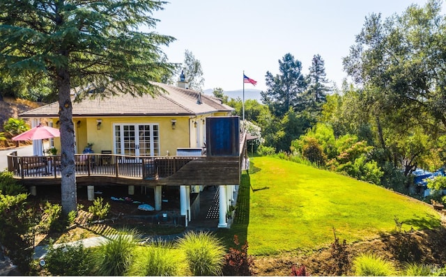 back of house featuring a wooden deck, a lawn, and french doors