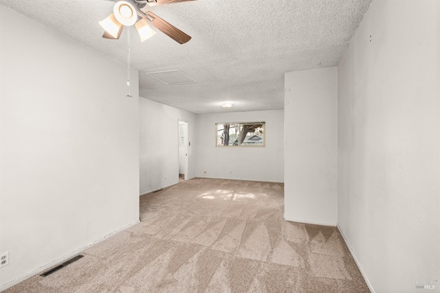 empty room featuring ceiling fan, light carpet, and a textured ceiling