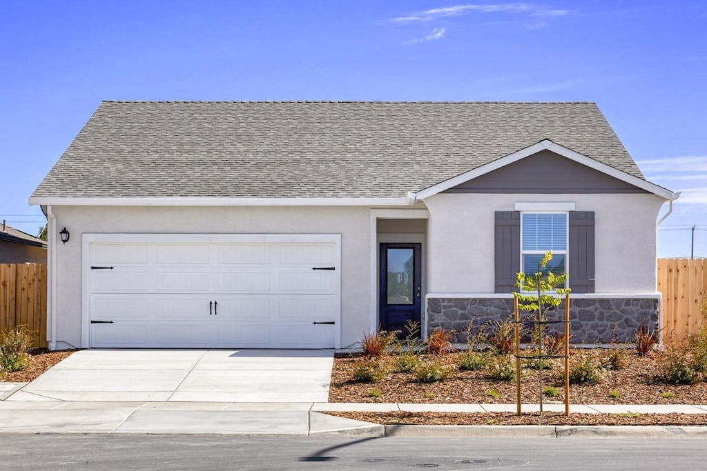 ranch-style house with an attached garage, a shingled roof, driveway, and fence