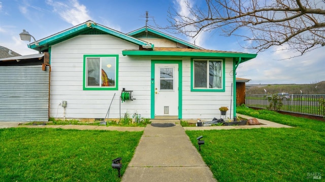 bungalow featuring fence and a front lawn