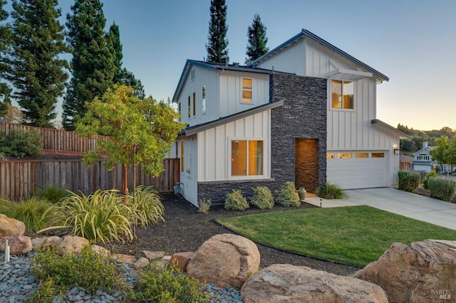 modern inspired farmhouse with board and batten siding, stone siding, fence, and concrete driveway